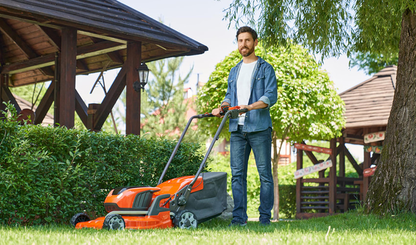 Landscaper standing next to a lawn mower in a garden