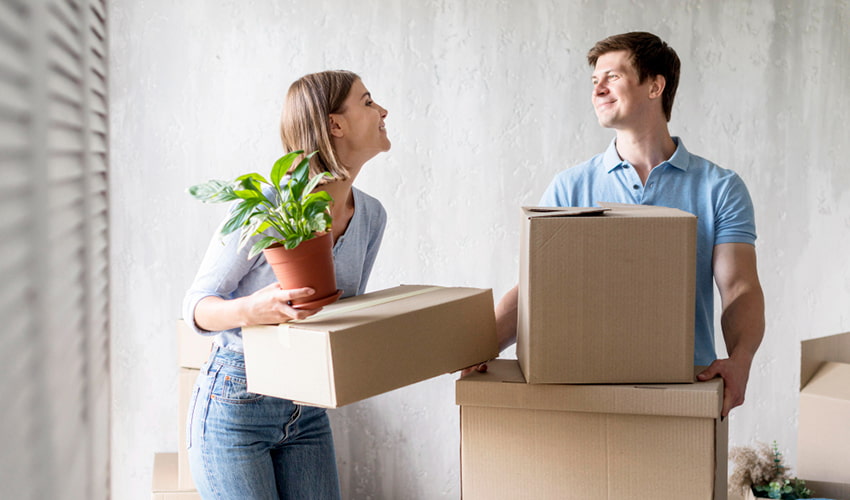 Couple carrying moving boxes while moving to a new home