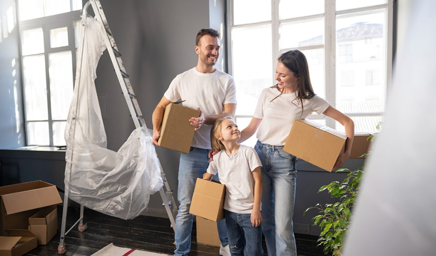 Family carrying moving boxes while moving into a new home